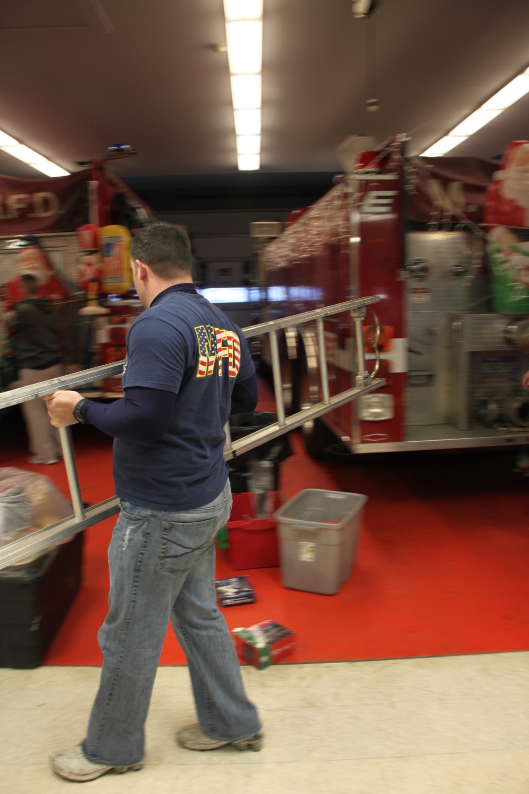 Firefighter moving a ladder inside the firehouse decorated for the holidays